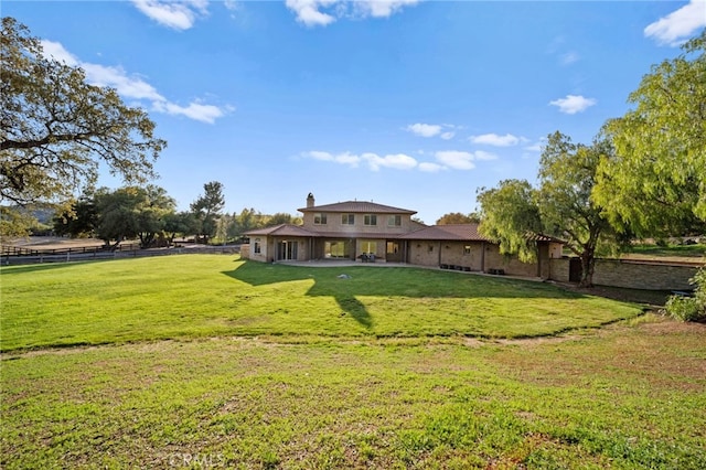 rear view of house featuring fence, a yard, and a patio area