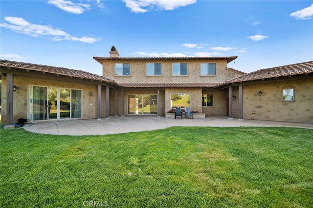 back of house with a lawn, a tiled roof, a patio, and stucco siding