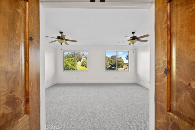 empty room featuring baseboards, ornamental molding, ceiling fan, and carpet flooring