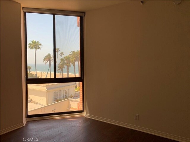 spare room with baseboards, a water view, and hardwood / wood-style flooring
