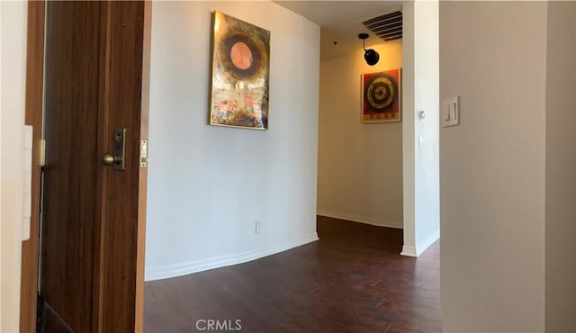corridor featuring visible vents, baseboards, and dark wood-type flooring