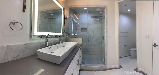 bathroom with baseboards, toilet, vanity, and a stall shower