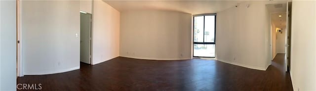 empty room featuring dark wood finished floors, baseboards, and plenty of natural light