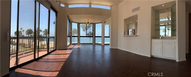 interior space with baseboards, visible vents, a towering ceiling, and dark wood-style floors