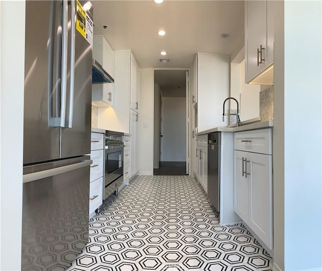 kitchen with oven, freestanding refrigerator, white cabinetry, visible vents, and recessed lighting
