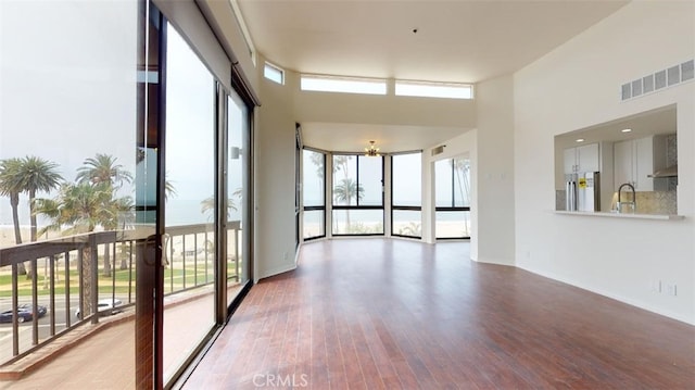 interior space with a sink, light wood-style floors, an inviting chandelier, a towering ceiling, and visible vents