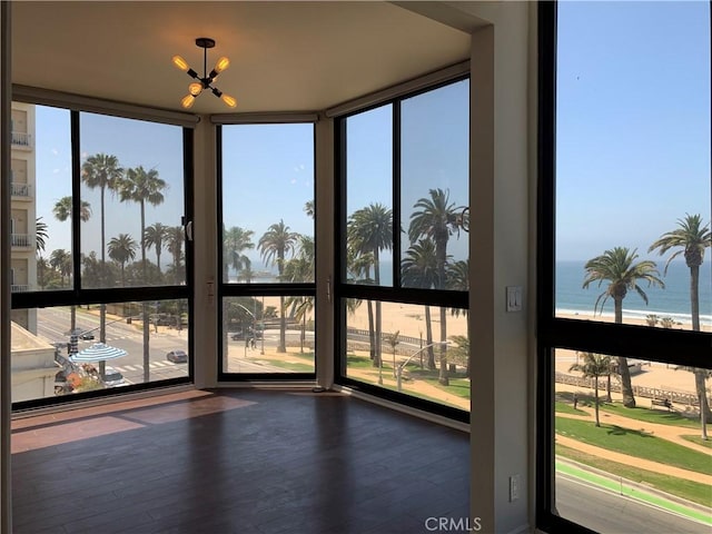 unfurnished sunroom featuring wood finished floors, a water view, and a wealth of natural light