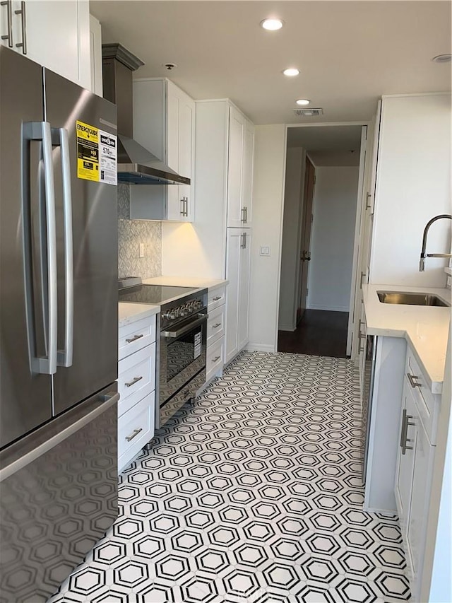 kitchen with recessed lighting, wall chimney range hood, electric stove, a sink, and freestanding refrigerator