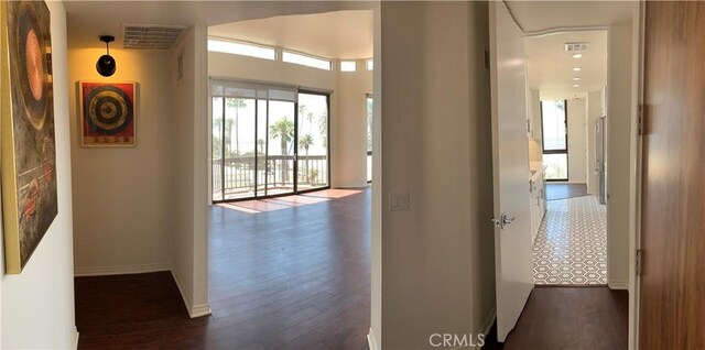hall featuring baseboards, visible vents, and dark wood-style floors