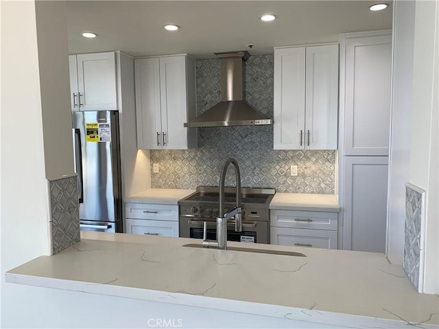 kitchen with wall chimney exhaust hood, stainless steel appliances, decorative backsplash, and white cabinetry