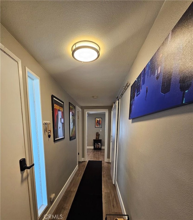 hallway with baseboards, a textured ceiling, and dark wood-style floors