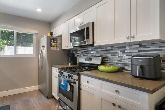 1192 Mitchell Ave Unit 66, Tustin, CA 92780 - kitchen with stainless steel appliances, white cabinetry, backsplash, light wood-style floors, and recessed lighting