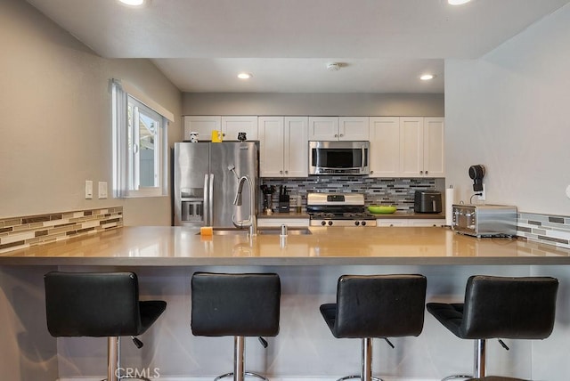 1192 Mitchell Ave Unit 66, Tustin, CA 92780 - kitchen with appliances with stainless steel finishes, backsplash, a sink, a peninsula, and white cabinetry