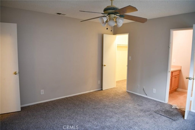 unfurnished bedroom with visible vents, ensuite bathroom, ceiling fan, a textured ceiling, and carpet flooring
