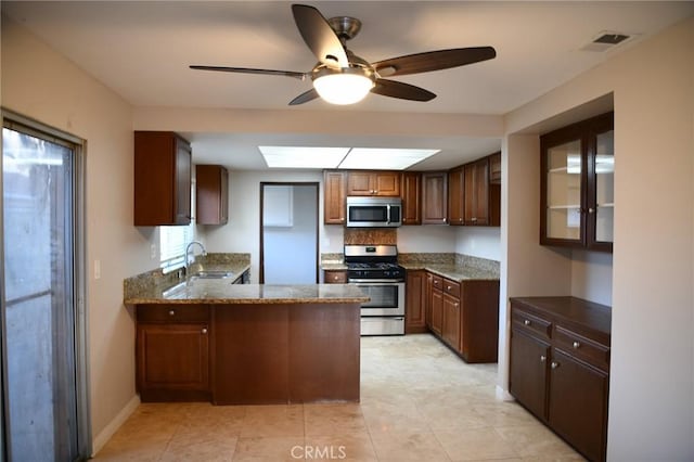 kitchen with appliances with stainless steel finishes, a peninsula, visible vents, ceiling fan, and a sink