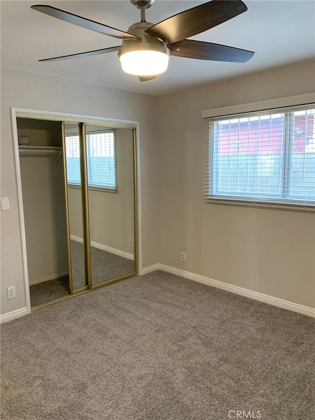 unfurnished bedroom featuring a closet, baseboards, multiple windows, and carpet flooring