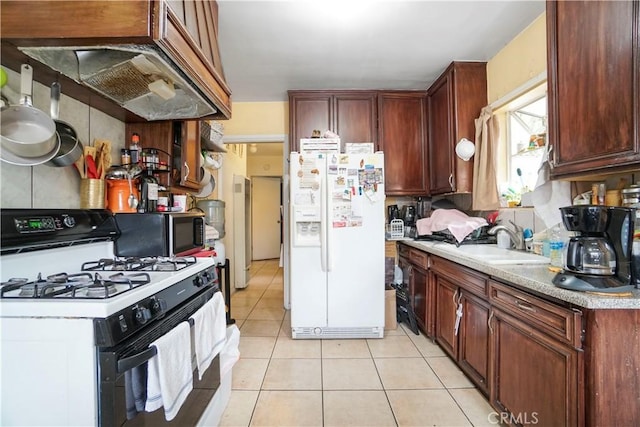 kitchen featuring white refrigerator with ice dispenser, light tile patterned flooring, stainless steel microwave, a sink, and range with gas cooktop