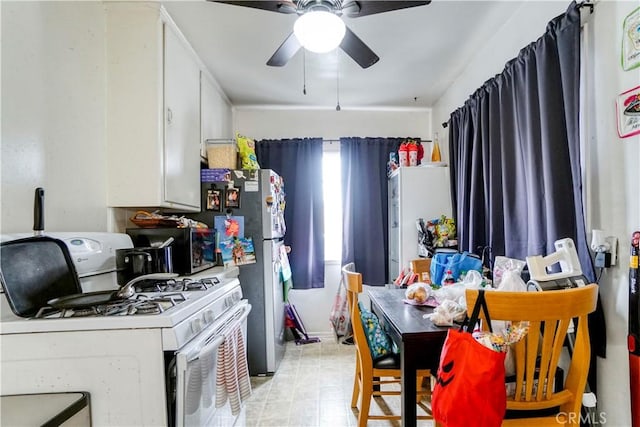 kitchen featuring white cabinets, ceiling fan, freestanding refrigerator, and white gas range