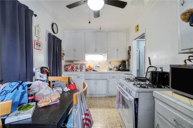 kitchen with white range with gas stovetop, a ceiling fan, white cabinets, stainless steel microwave, and a sink