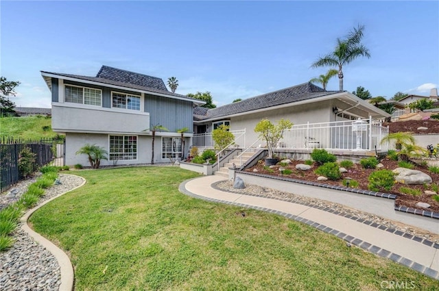 view of front of property with fence private yard, stucco siding, and a front lawn