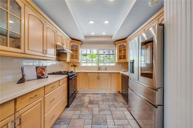 kitchen featuring stone finish floor, light brown cabinetry, black appliances, under cabinet range hood, and light countertops
