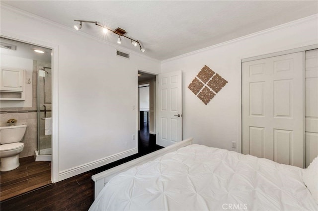 bedroom with dark wood-style flooring, a closet, ornamental molding, ensuite bathroom, and visible vents