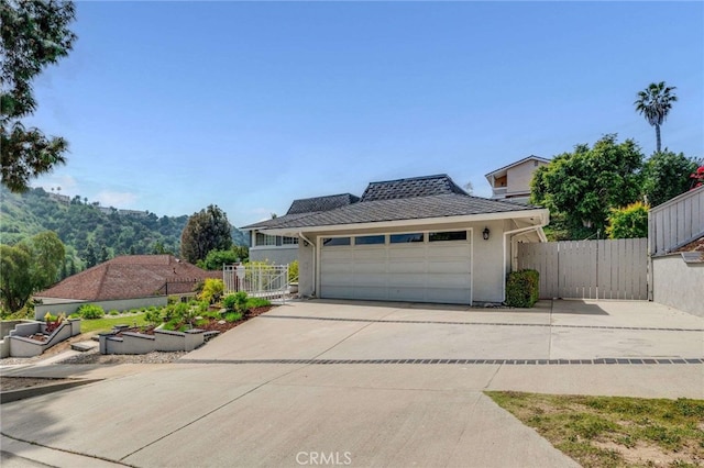 exterior space featuring stucco siding, fence, a gate, an attached garage, and concrete driveway