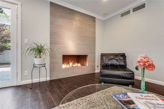 living area with crown molding, a large fireplace, visible vents, wood finished floors, and baseboards