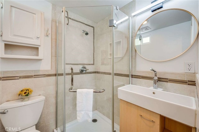 full bath featuring a shower stall, vanity, tile walls, and toilet