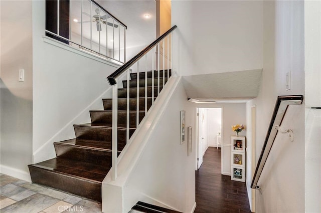 stairs with baseboards, a high ceiling, and wood finished floors