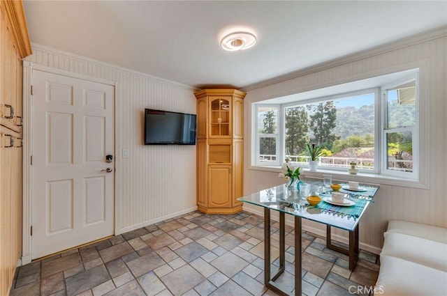 dining area featuring ornamental molding, baseboards, and stone finish floor