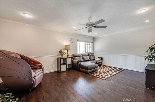 living area with a ceiling fan, a textured ceiling, crown molding, wood finished floors, and a wainscoted wall