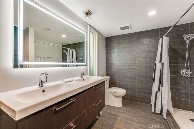 bathroom with tiled shower, a sink, visible vents, and tile walls