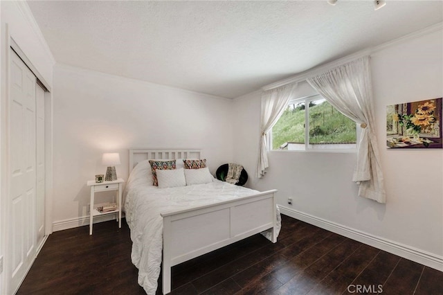 bedroom featuring a closet, baseboards, crown molding, and wood finished floors