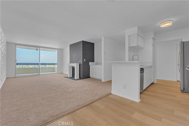 28121 Highridge Rd Unit 402, Rancho Palos Verdes, CA 90275 - kitchen with a brick fireplace, light countertops, a wall of windows, light wood-type flooring, and stainless steel appliances
