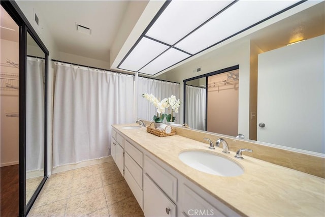 full bathroom with double vanity, visible vents, a spacious closet, and a sink
