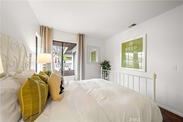bedroom with visible vents, wood finished floors, and baseboards
