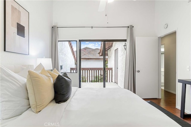 bedroom with access to outside, wood finished floors, and a high ceiling