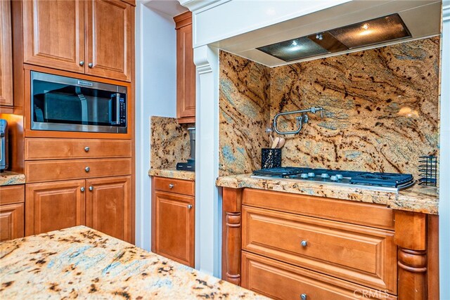 1550 Hibiscus Ave, Azusa, CA 91702 - kitchen featuring premium range hood, brown cabinetry, stainless steel appliances, backsplash, and light stone counters