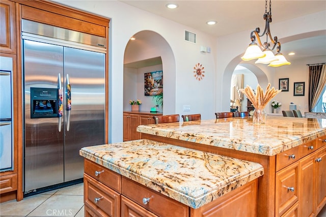 1550 Hibiscus Ave, Azusa, CA 91702 - kitchen with built in refrigerator, arched walkways, visible vents, a center island, and brown cabinets