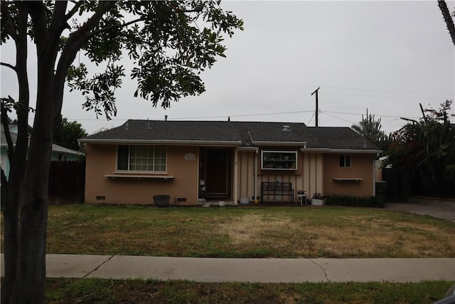 view of front of house featuring board and batten siding, fence, a shingled roof, and a front yard