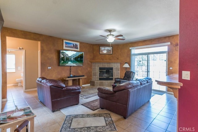 living room with light tile patterned floors, baseboards, a ceiling fan, and a fireplace