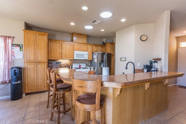 kitchen featuring light tile patterned floors, a sink, white appliances, and visible vents