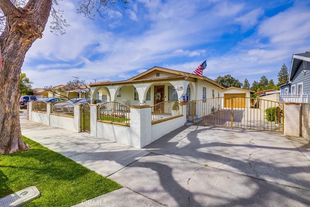 1127 W Myrtle St, Santa Ana, CA 92703 - view of front of house with stucco siding, a fenced front yard, a porch, an outbuilding, and a gate