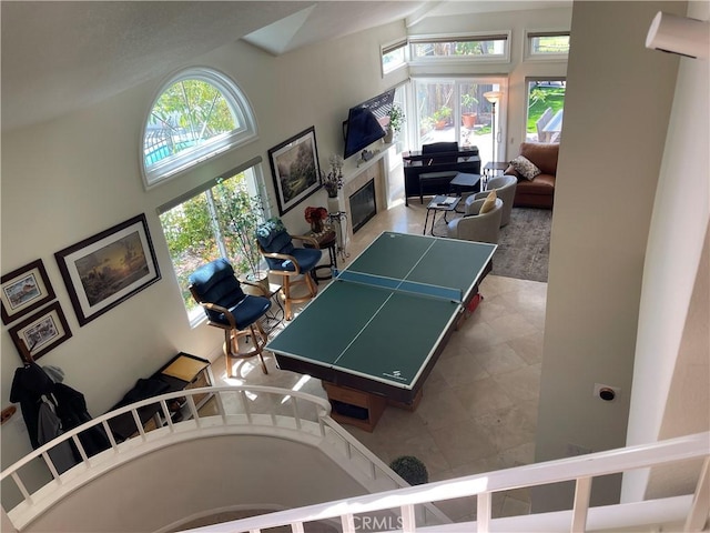 game room with a glass covered fireplace and high vaulted ceiling