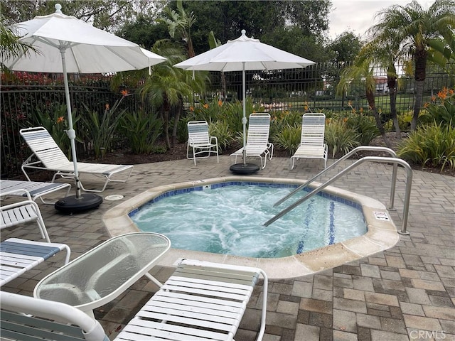 view of pool with a community hot tub, a patio, and fence