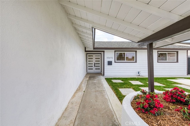 view of exterior entry featuring a shingled roof