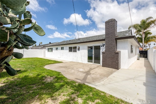 back of house with a fenced backyard, stucco siding, a lawn, a patio area, and a chimney
