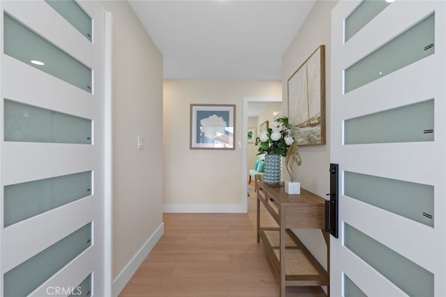 hallway with light wood-type flooring and baseboards