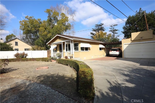 bungalow-style home with a carport, covered porch, concrete driveway, fence, and stucco siding